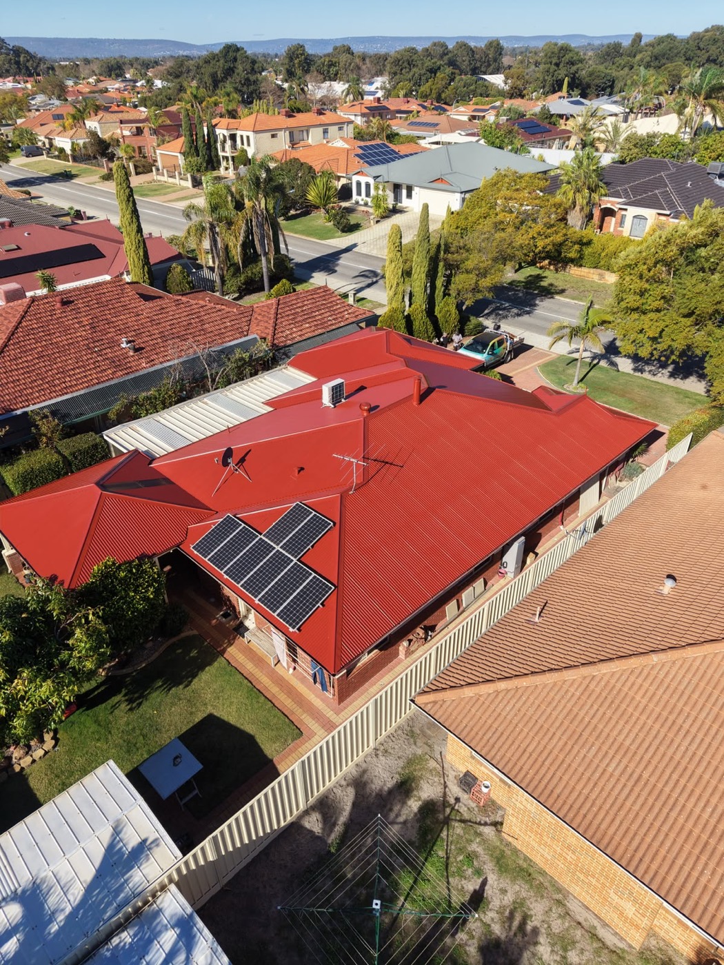 Terracotta roof with solar panels after HydroFlow restoration, fresh red finish