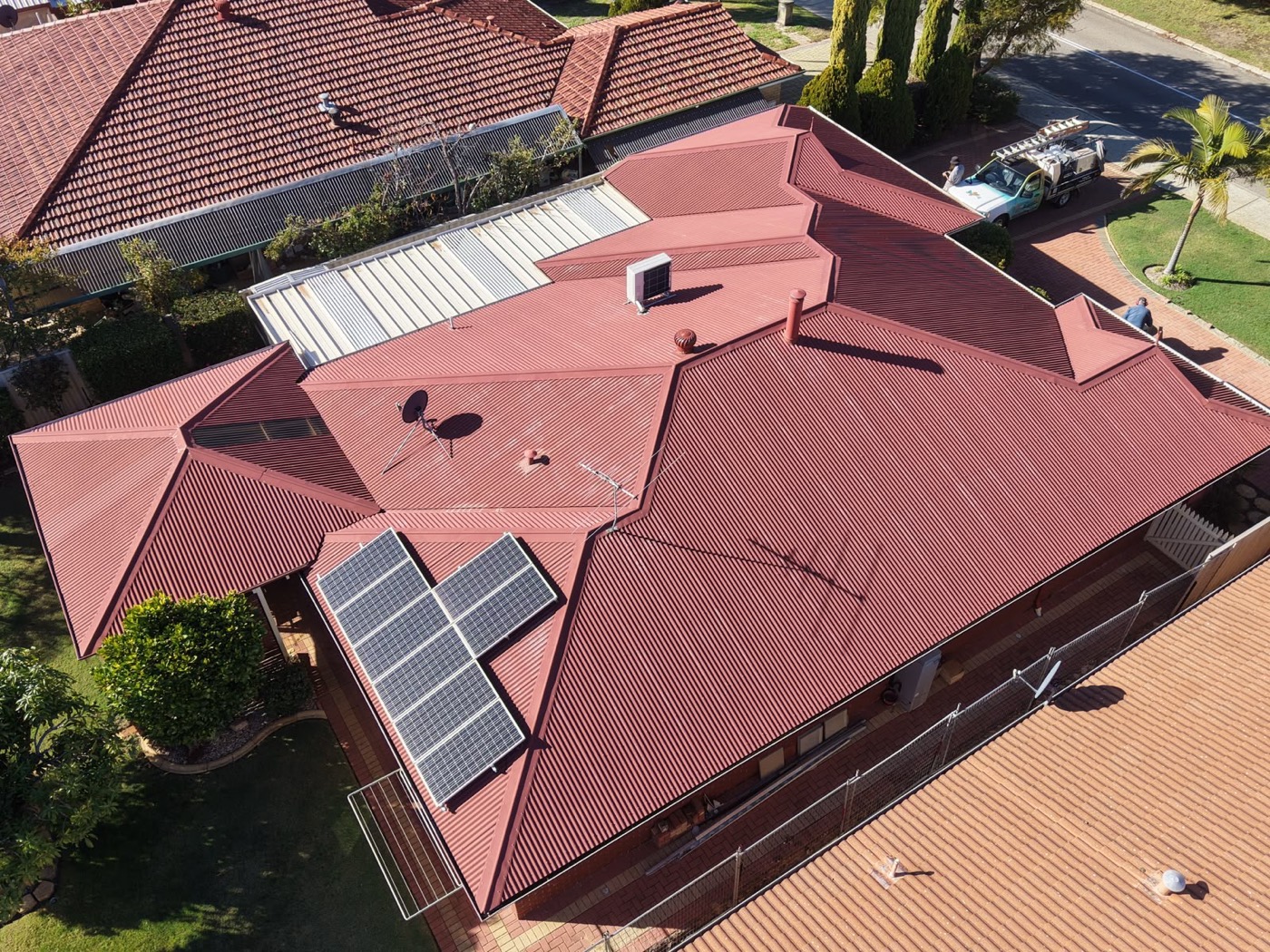 Terracotta roof with solar panels before restoration, faded and weathered